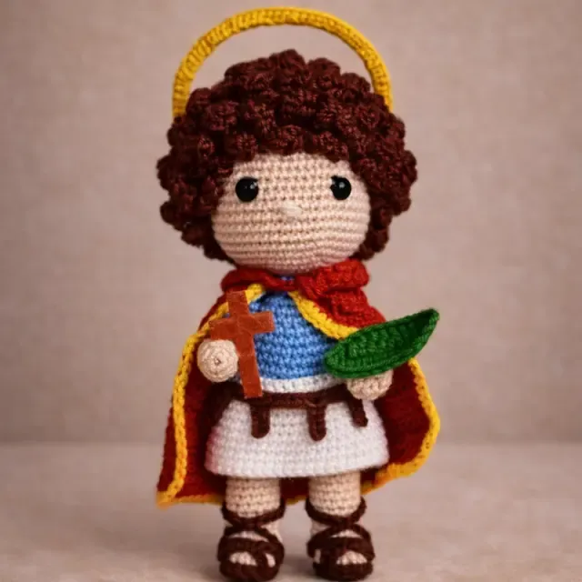 Santo amigurumi com halo dourado, segurando criança e folhas